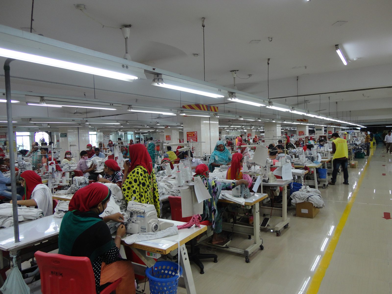 Rows of sewing machines and workers on a garment factory floor in Bangladesh.
