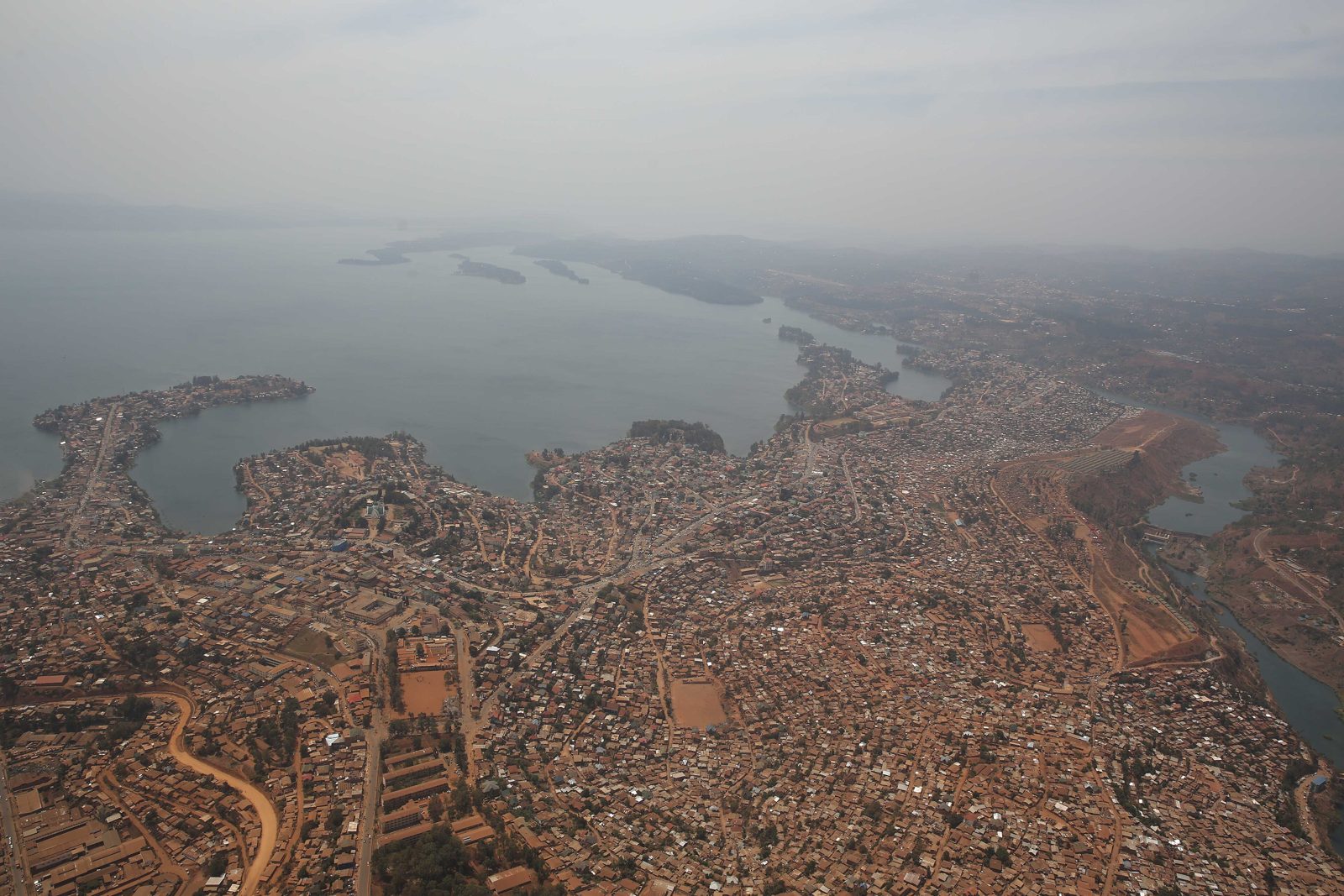 Aerial view of Bukavu on the shore of Lake Kivu, dense low-rise housing along the water.
