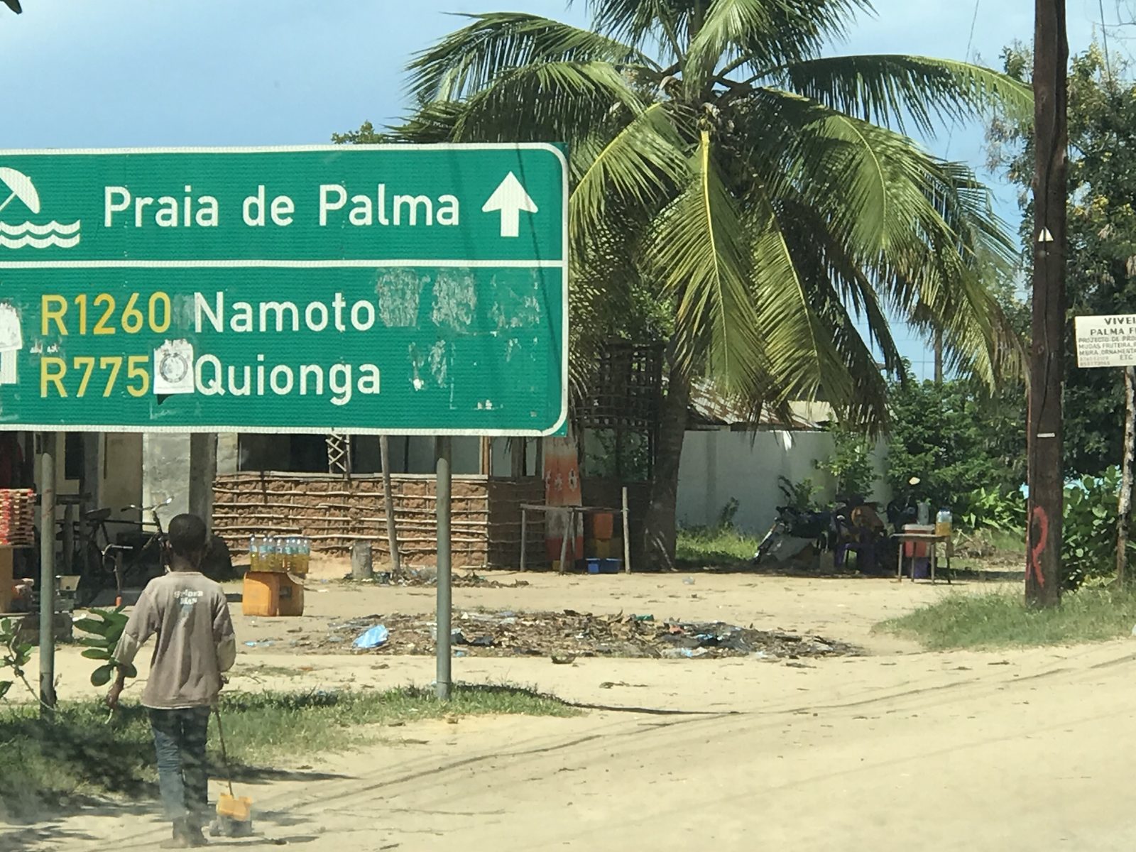 A green road sign in Palma, Cabo Delgado, pointing to Praia de Palma, Namoto and Quionga.